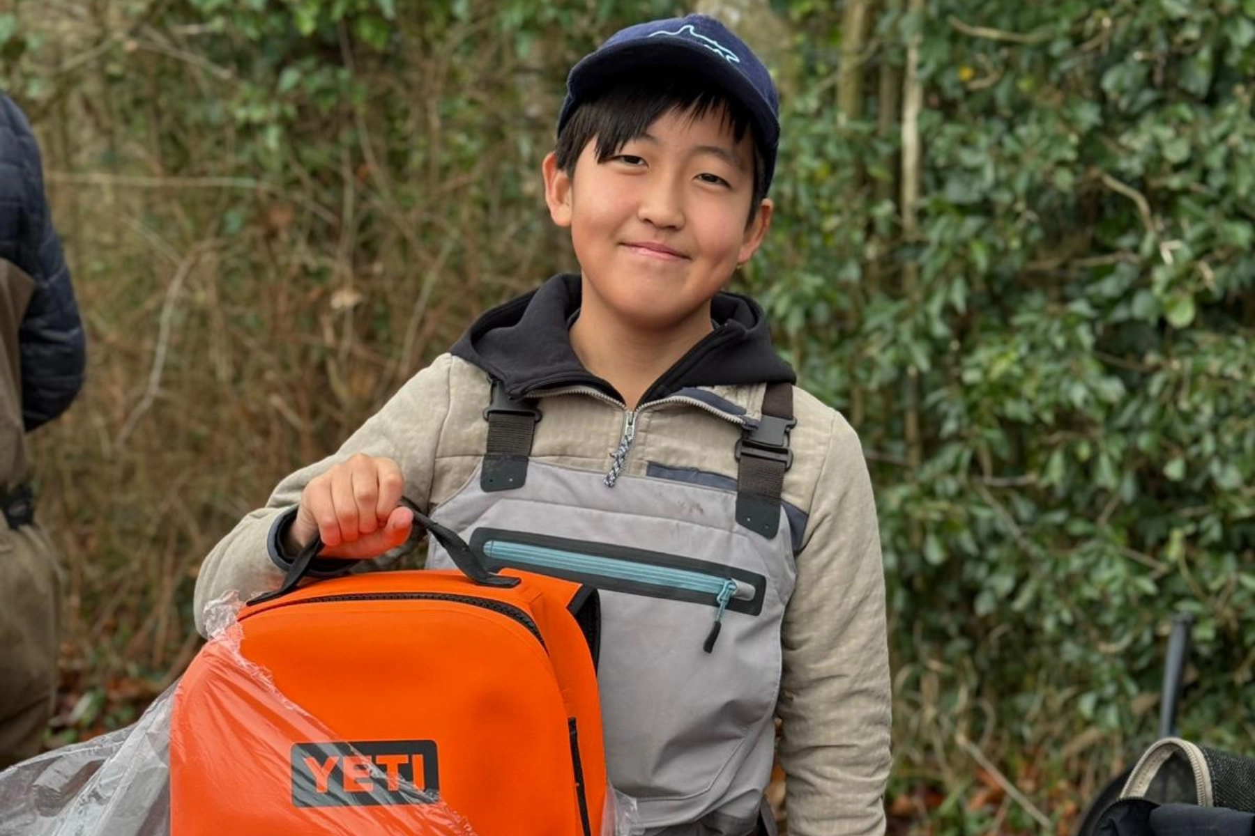 A young angler proudly geared up and ready for a challenging weekend of river training.